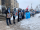 A line of people holding photographs and signs stand outside government buildings.